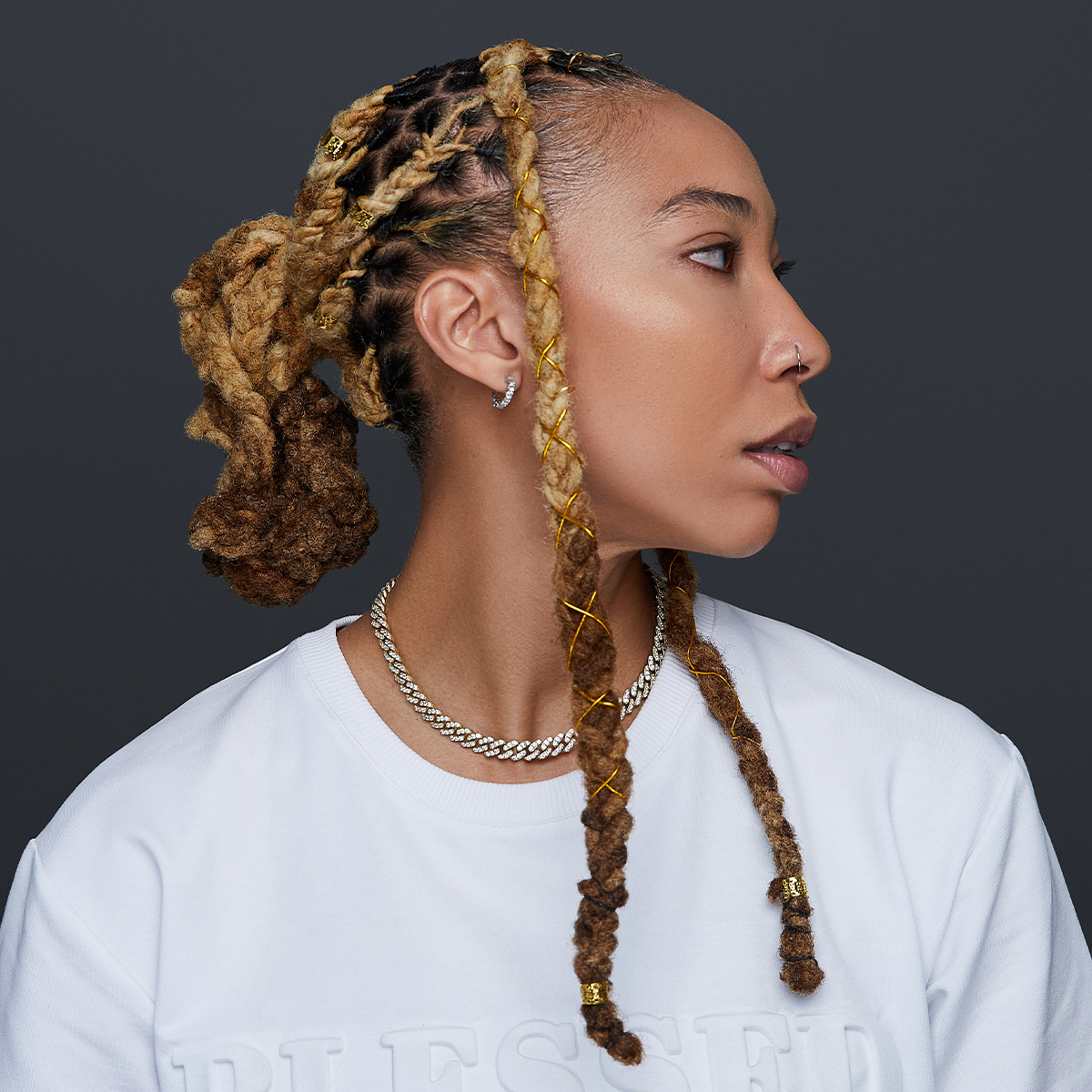 A woman with several braids in her hair adorned with gold braid charms from KISS Colors and Care.