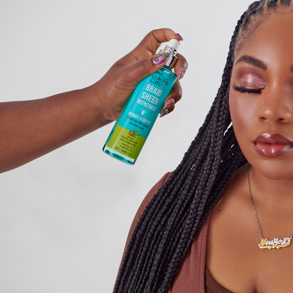 A person spraying Braid Sheen Refresher spray from KISS Colors and Care on a woman&