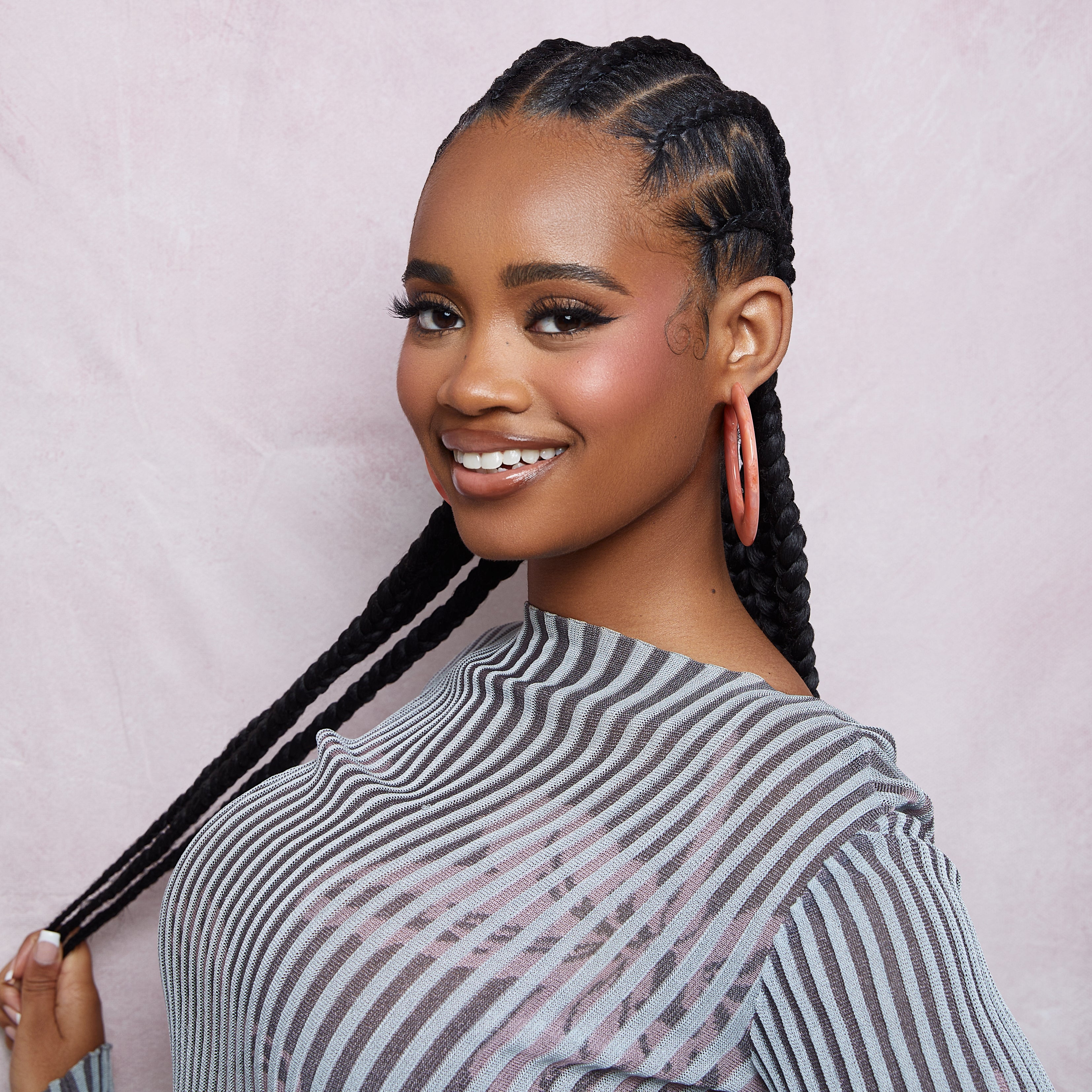 A woman with braids and fun design done by using KISS Colors & Care Pin Tail Axe Parting Comb.
