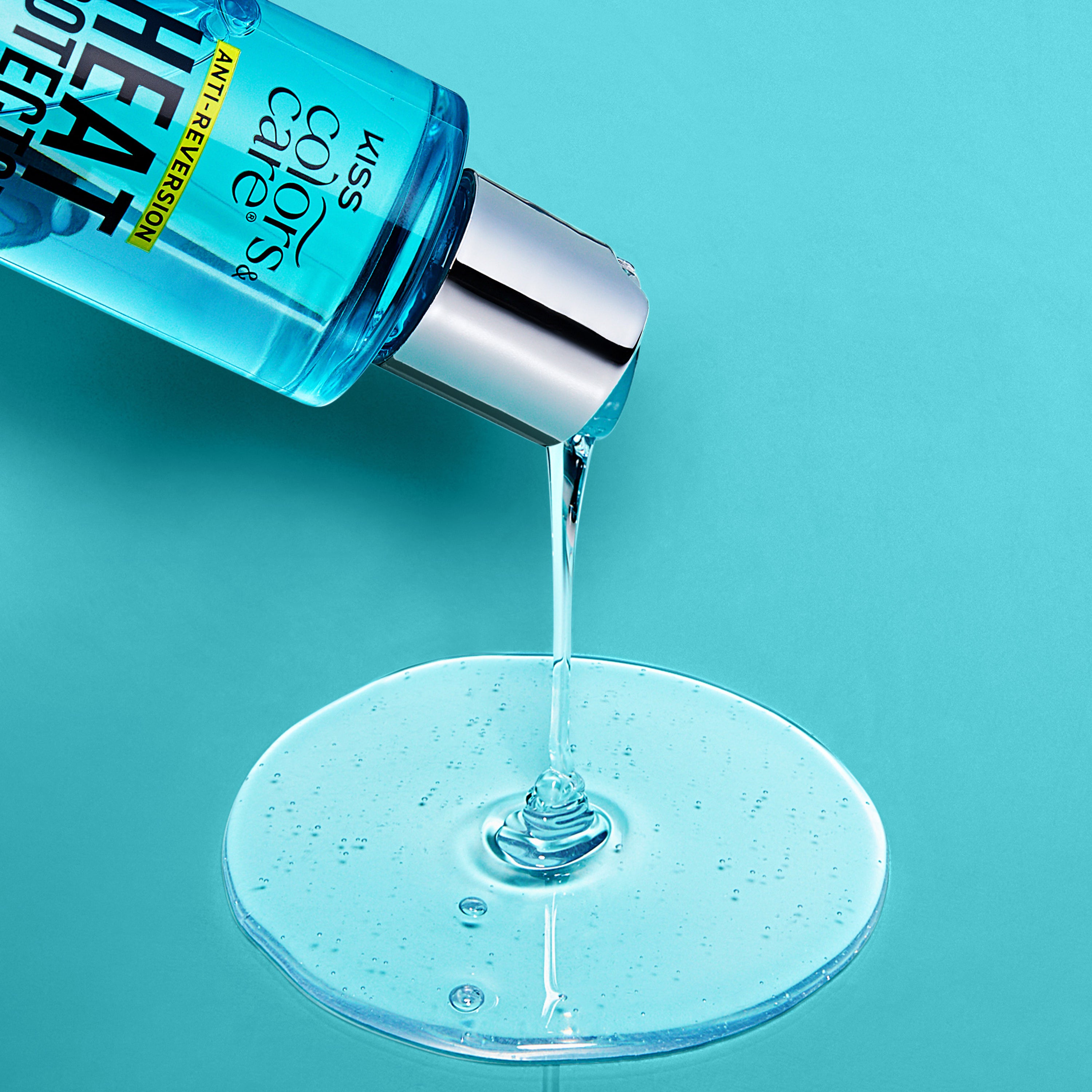 Blue KISS Colors &amp; Care hair oil serum bottle tilted, pouring clear liquid onto a bright blue surface with "Anti-Reversion" label visible.