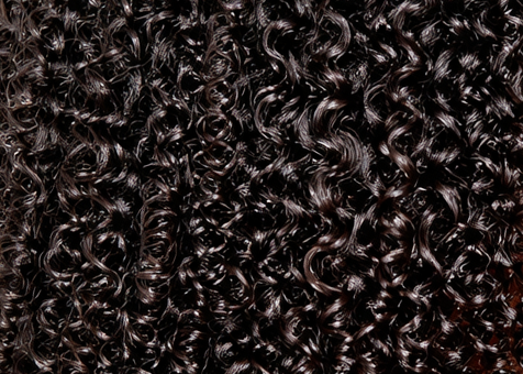 Tightly coiled, glossy black hair curls filling the frame, showcasing natural texture and shine.