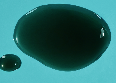 Two glossy dark green gel capsules on a light blue background, highlighting the product's smooth texture.