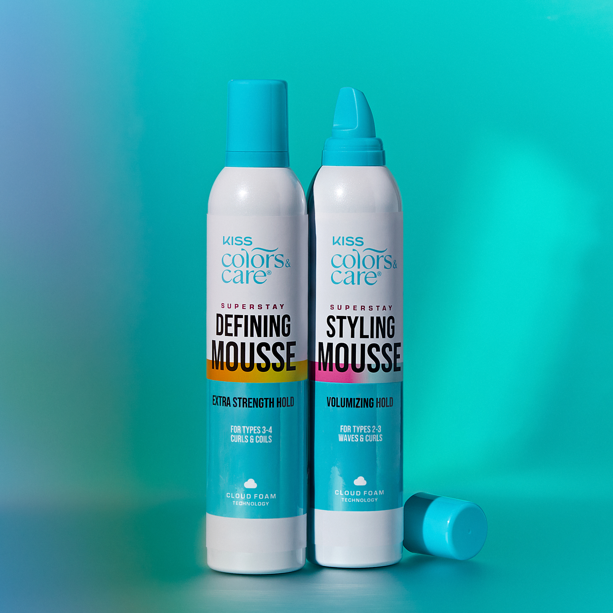 Two white and turquoise cans of KISS Colors &amp; Care Superstay hair mousse on a blue-green background; one for extra strength hold curls 3-4, the other for volumizing hold waves and curls 2-3.