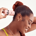 Woman with braided hair applies pink Edge Fixer Wax Stick labeled "Max Hold Hair Wax Stick Sweet Peach" to smooth baby hairs.