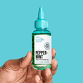 Hand holding a small clear bottle of KISS Colors &amp; Care Peppermint Multivitamin Oil with a turquoise cap, labeled to stimulate and refresh with biotin and vitamin E boost.